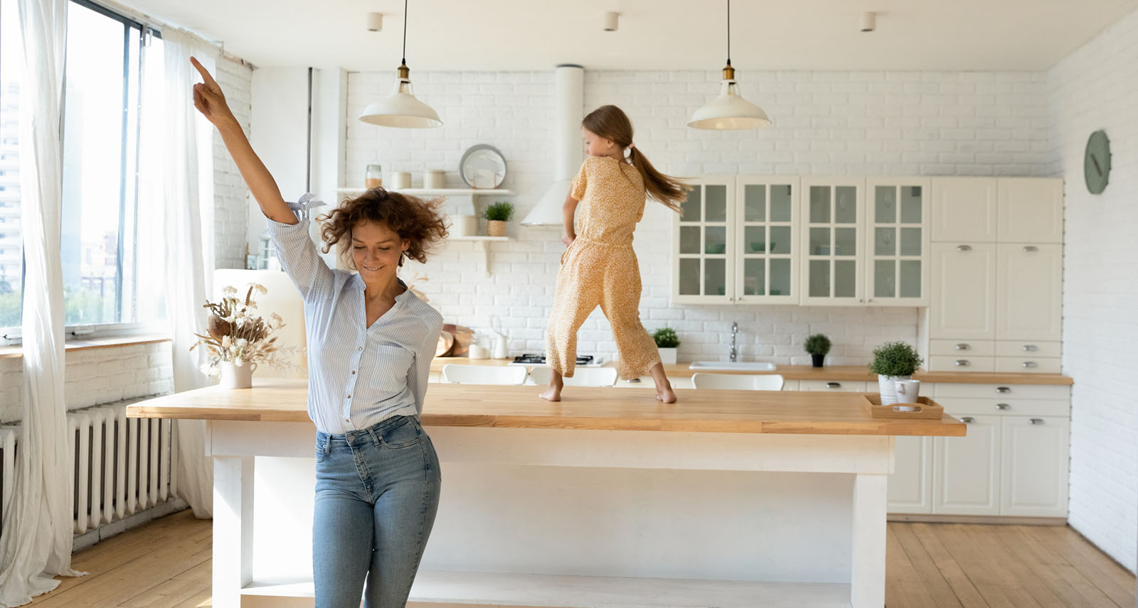 Happy young mom and little daughter dance at home